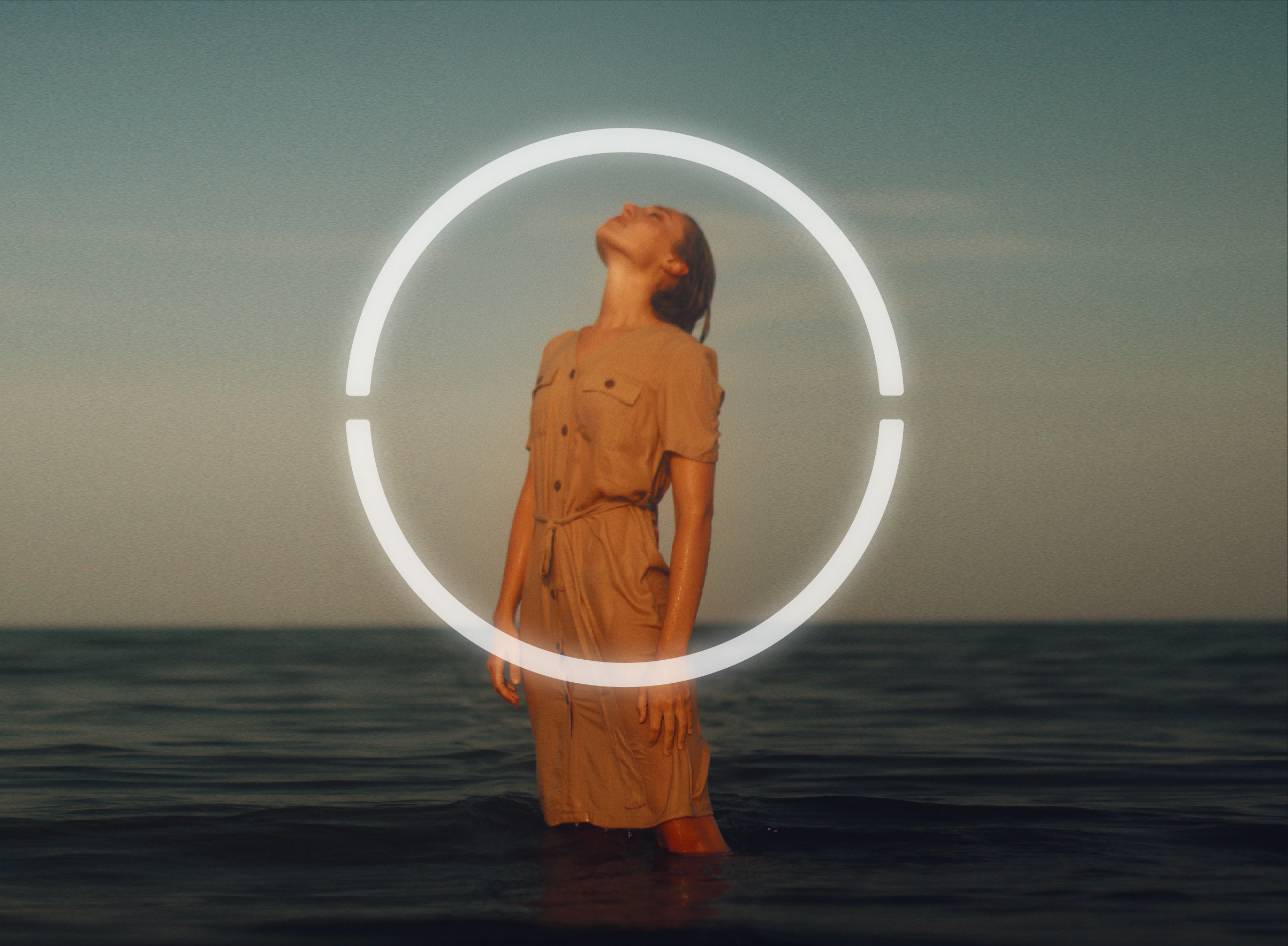 Fotografía de mujer en el mar posando un vestido de moda sustentable. Sobre la imagen esta el isotipo de la marca.